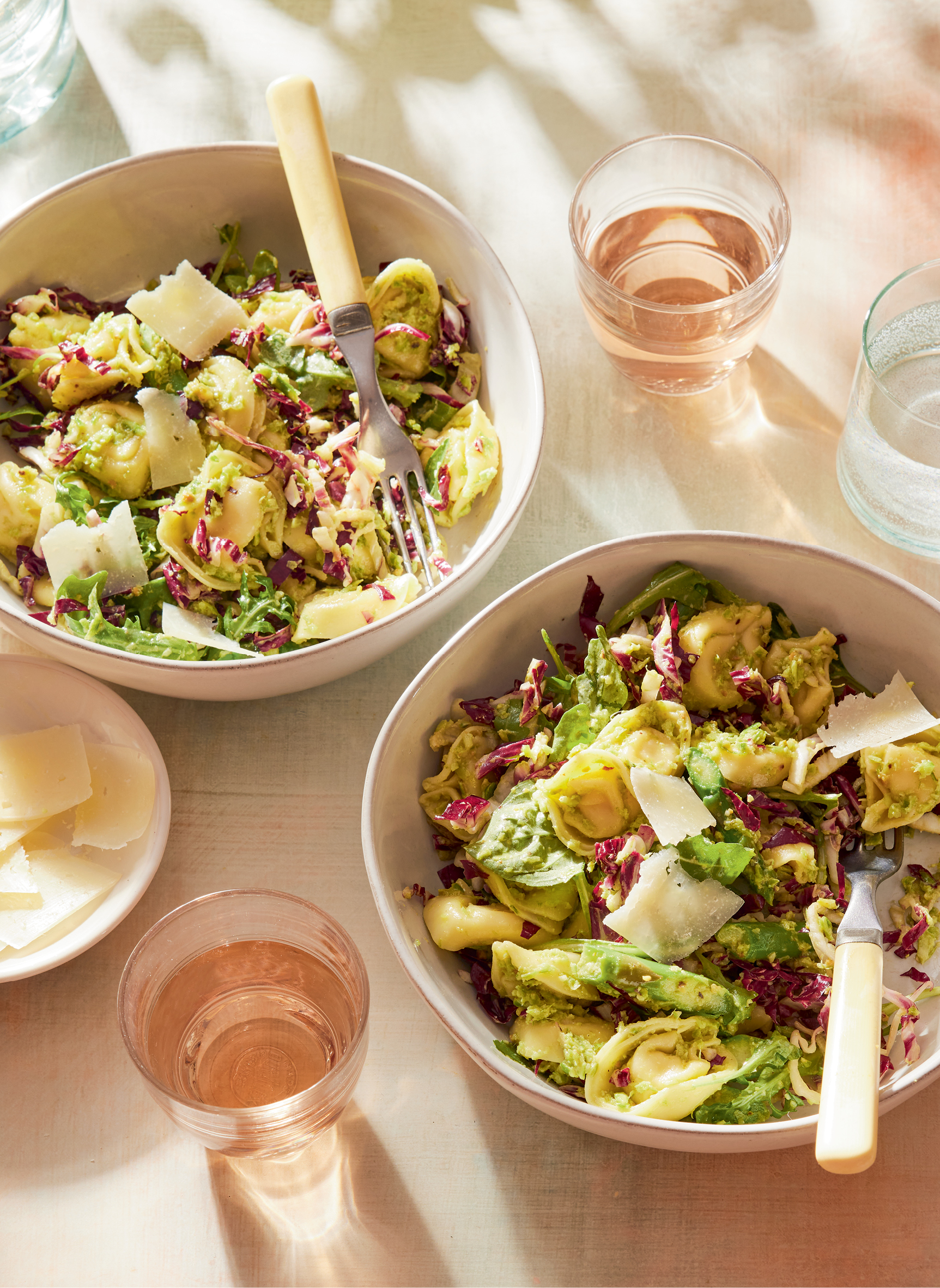 Two bowls of tortellini salad, set with glasses of rosé.