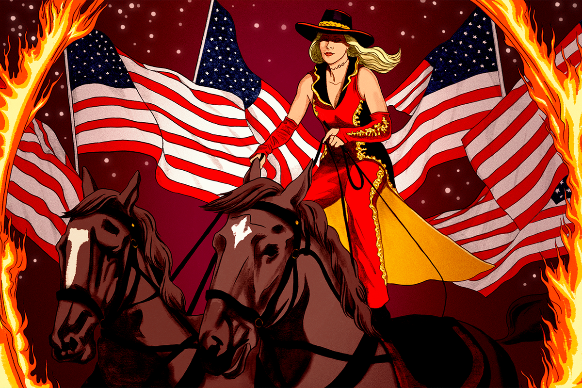 A woman standing atop two horses rides them through a ring of fire as American flags fly in the background. The scene captures one of the acts performed during the popular tourist attraction Dolly Parton’s Stampede.