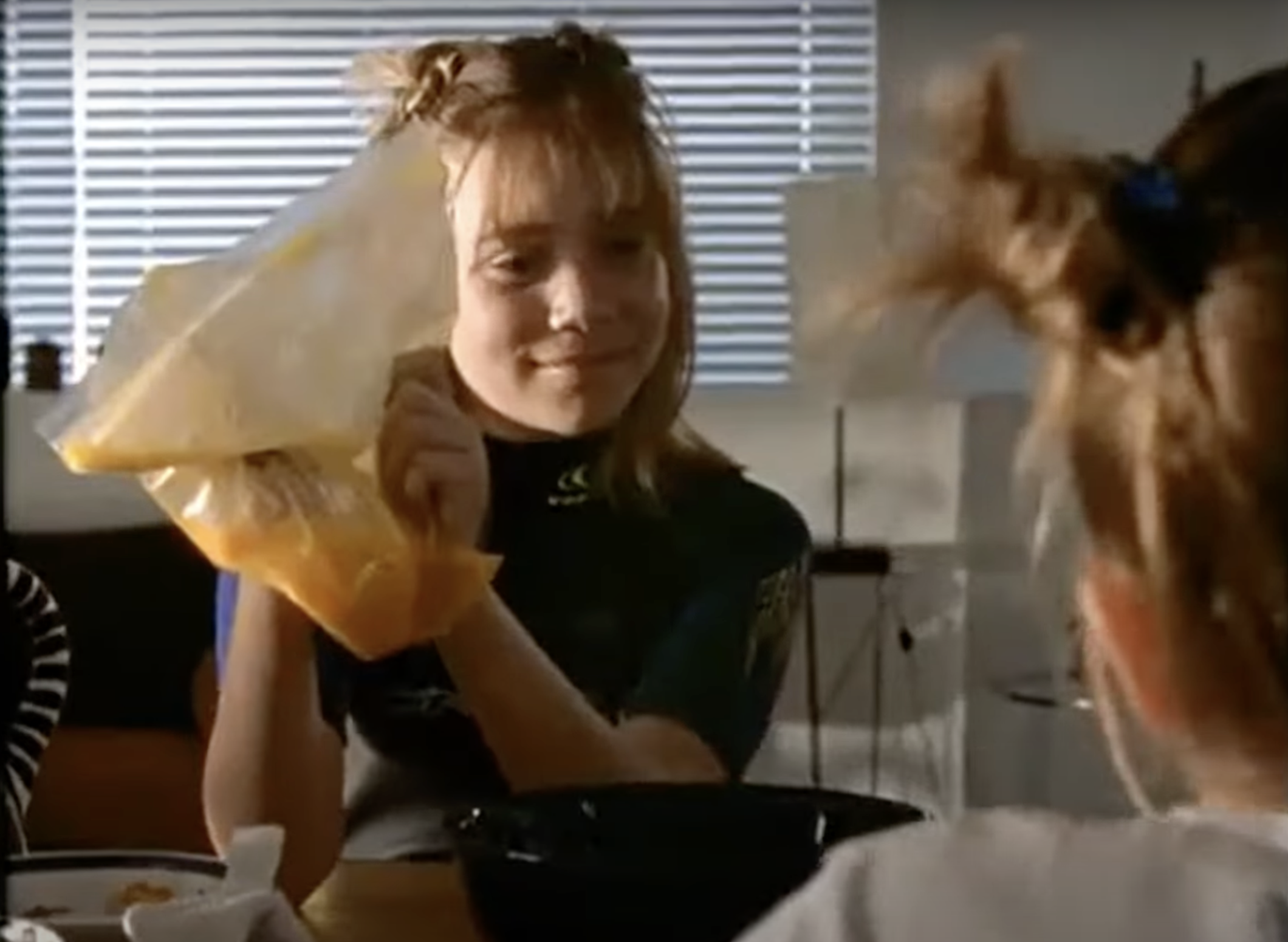 A screenshot of a young Ashley Olsen shaking a bag of scrambled eggs in the 1998 movie “Billboard Dad”